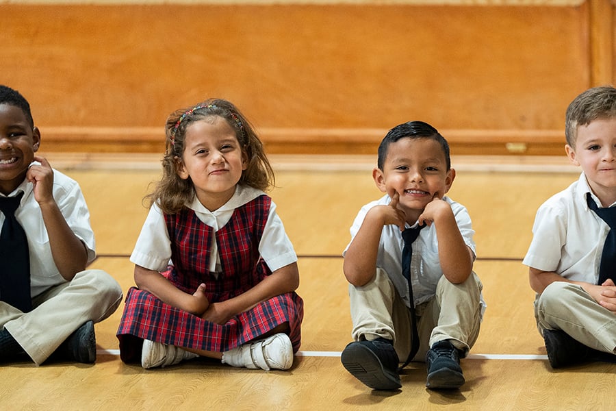 Pre-kindergartners make funny faces while waiting to return to their classroom at St. Peter the Apostle Catholic Classical School on May 12, 2023.